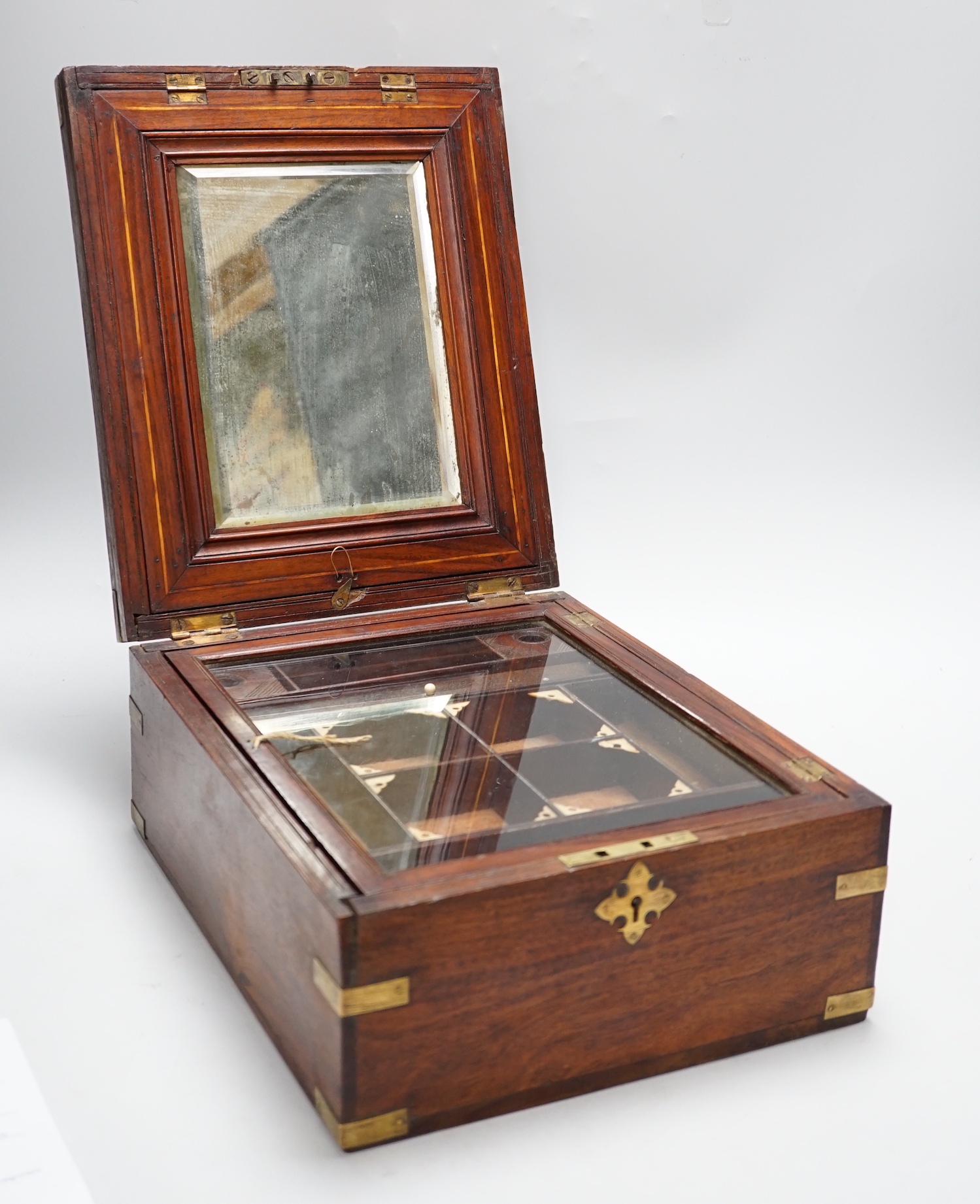 An Anglo-Indian wooden brass bound sewing box, with fitted interior and removable sections, hinged bevelled mirror, internal glass lid, etc. lock marked Birmingham, 26cm x 31cm x 14cm